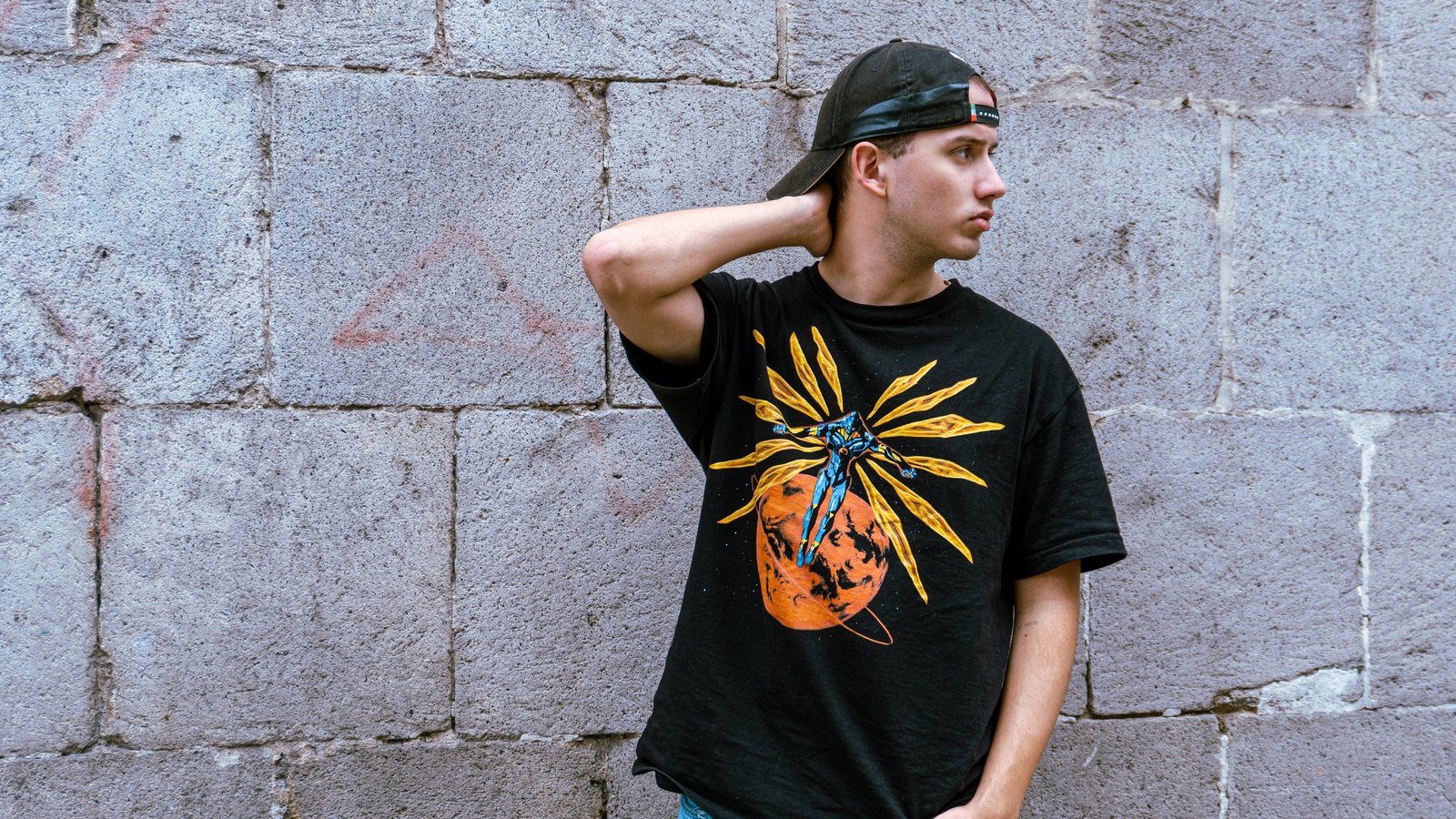 Modelo con camiseta gráfica frente a pared de piedra