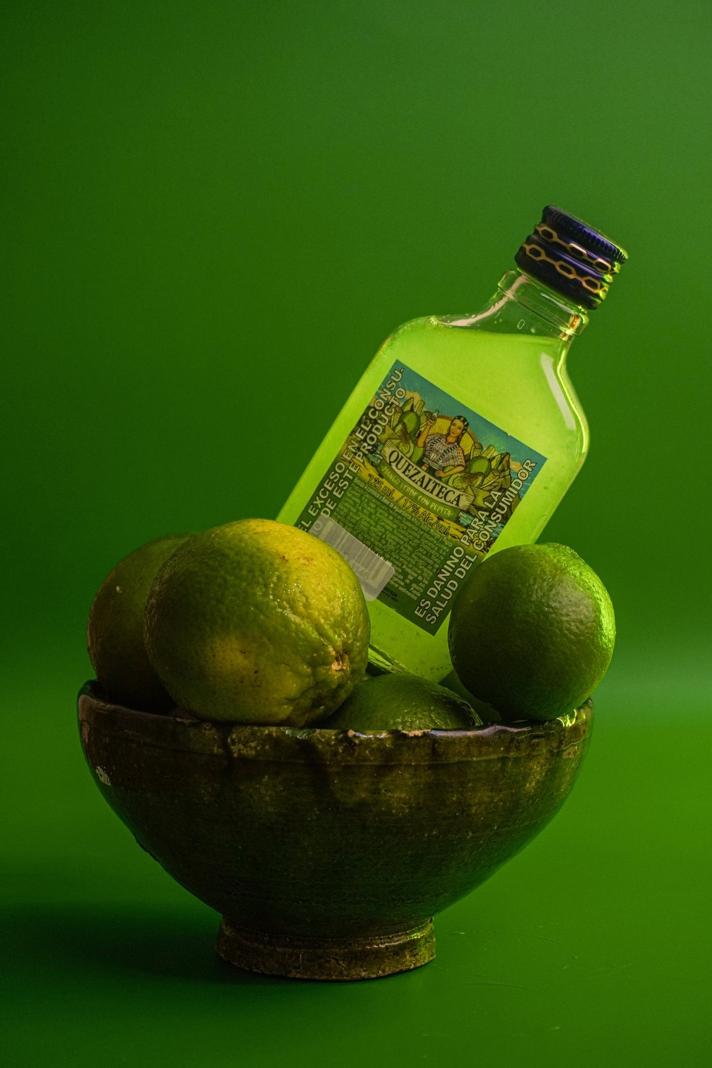 Botella verde en un cuenco con limones